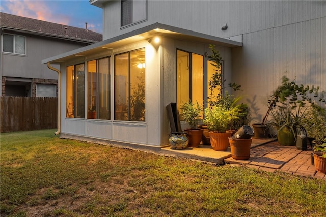 property exterior at dusk with a yard and a sunroom