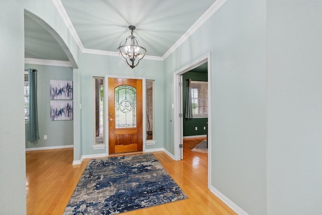 foyer with hardwood / wood-style flooring, a notable chandelier, and ornamental molding