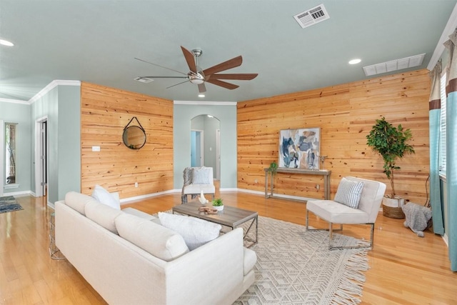 living room featuring hardwood / wood-style flooring, wood walls, and crown molding