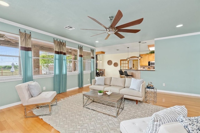 living room with ceiling fan, crown molding, and light hardwood / wood-style floors