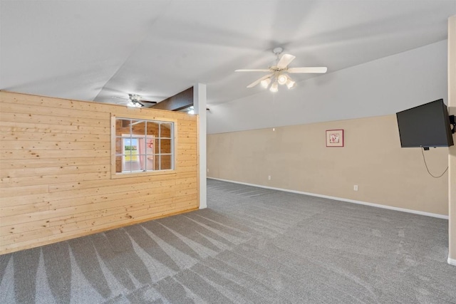 unfurnished room featuring carpet, ceiling fan, lofted ceiling, and wood walls