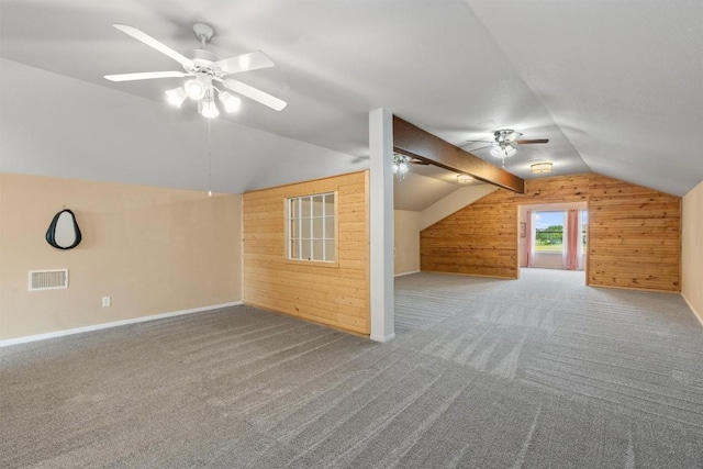 bonus room featuring carpet flooring, wooden walls, ceiling fan, and vaulted ceiling