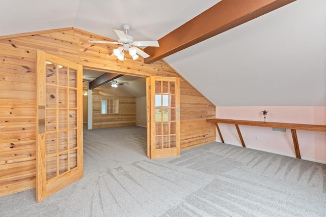 additional living space featuring carpet, ceiling fan, wood walls, and lofted ceiling with beams