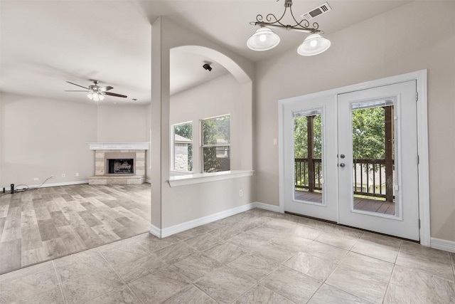 entryway featuring ceiling fan, light tile patterned floors, a tile fireplace, and french doors