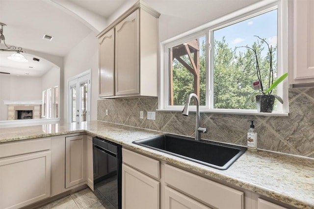 kitchen with tasteful backsplash, dishwasher, sink, and light stone counters