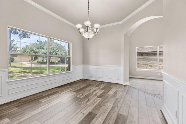 unfurnished dining area featuring a notable chandelier, ornamental molding, and light hardwood / wood-style flooring