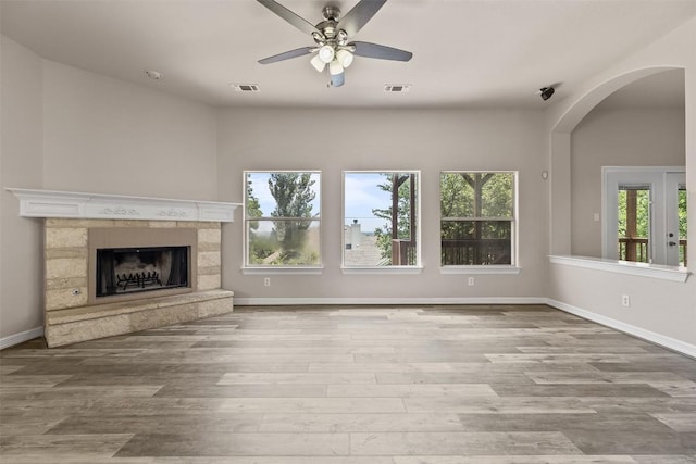 unfurnished living room featuring a fireplace, light hardwood / wood-style floors, and ceiling fan