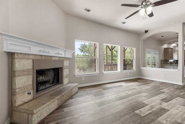 unfurnished living room featuring ceiling fan, a fireplace, and wood-type flooring