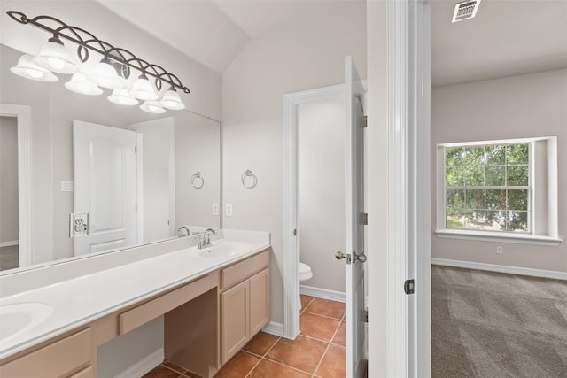 bathroom with tile patterned flooring, vanity, vaulted ceiling, and toilet