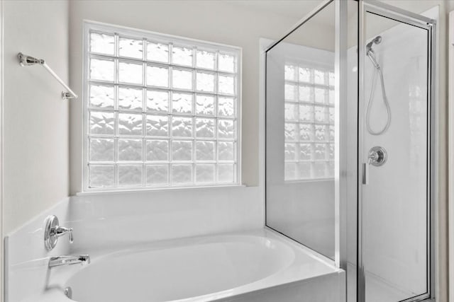 bathroom with shower with separate bathtub and a wealth of natural light