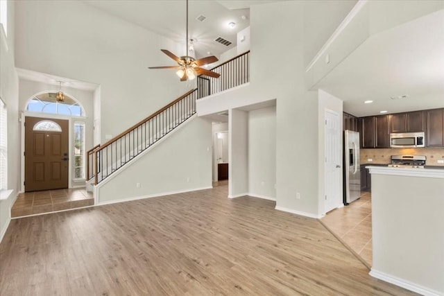 entryway featuring ceiling fan, light hardwood / wood-style floors, and a high ceiling