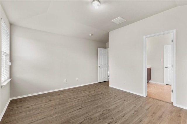 empty room featuring hardwood / wood-style floors, lofted ceiling, and a healthy amount of sunlight