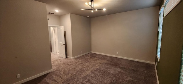 empty room featuring carpet and a chandelier