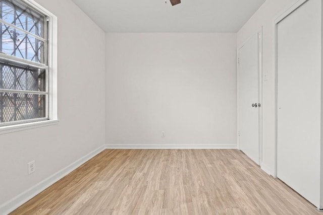 spare room with light wood-type flooring, a wealth of natural light, and ceiling fan