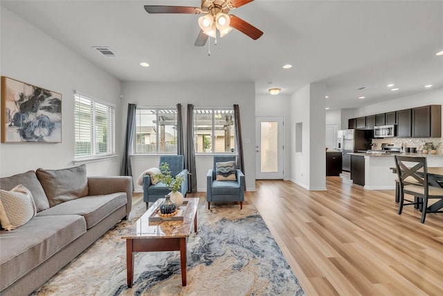 living room with ceiling fan and light hardwood / wood-style flooring