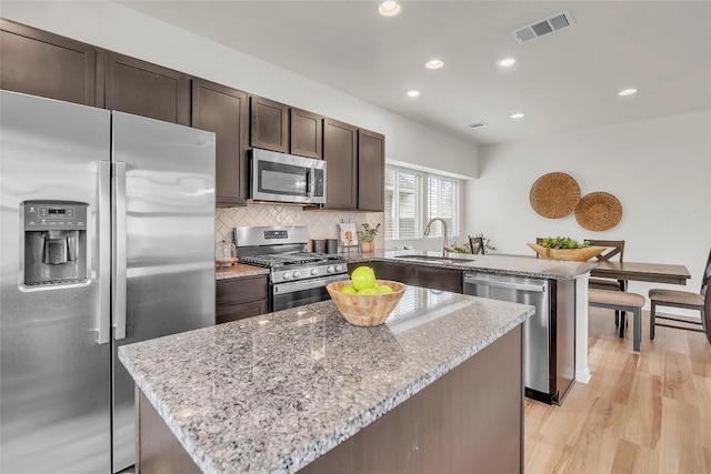 kitchen featuring light stone countertops, sink, a center island, and appliances with stainless steel finishes