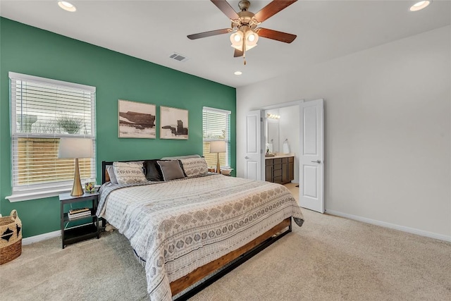 bedroom with ceiling fan, ensuite bathroom, and light carpet