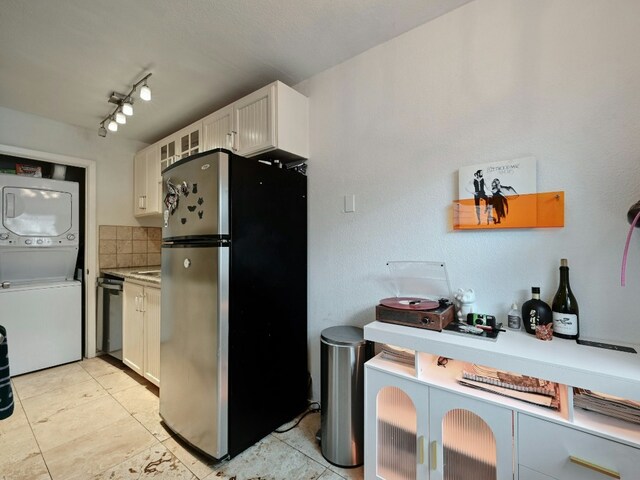 kitchen featuring decorative backsplash, stacked washer and dryer, stainless steel appliances, and white cabinetry