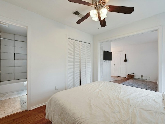 bedroom with ensuite bathroom, ceiling fan, and dark wood-type flooring