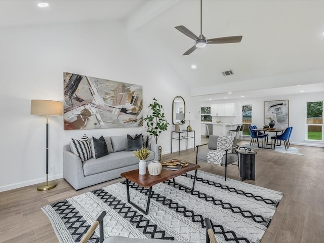 living room featuring beam ceiling, ceiling fan, high vaulted ceiling, and light wood-type flooring