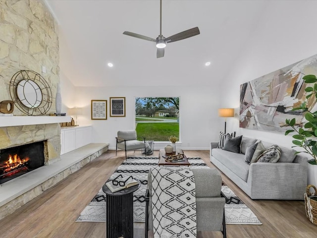 living room with ceiling fan, a fireplace, high vaulted ceiling, and wood-type flooring