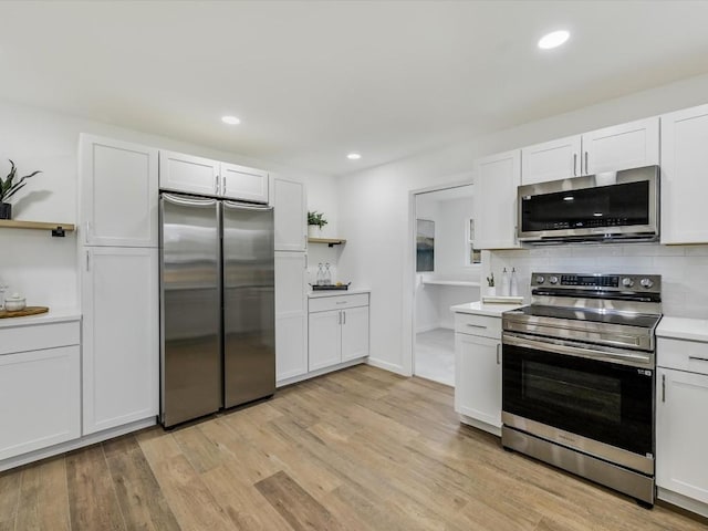 kitchen featuring white cabinets, tasteful backsplash, appliances with stainless steel finishes, and light hardwood / wood-style flooring