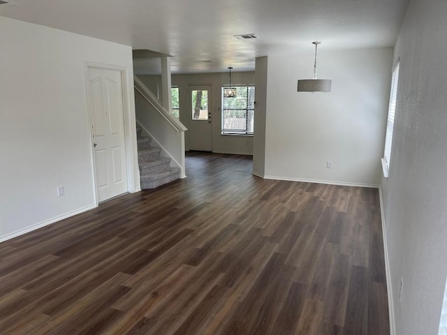 unfurnished living room with dark hardwood / wood-style floors and an inviting chandelier