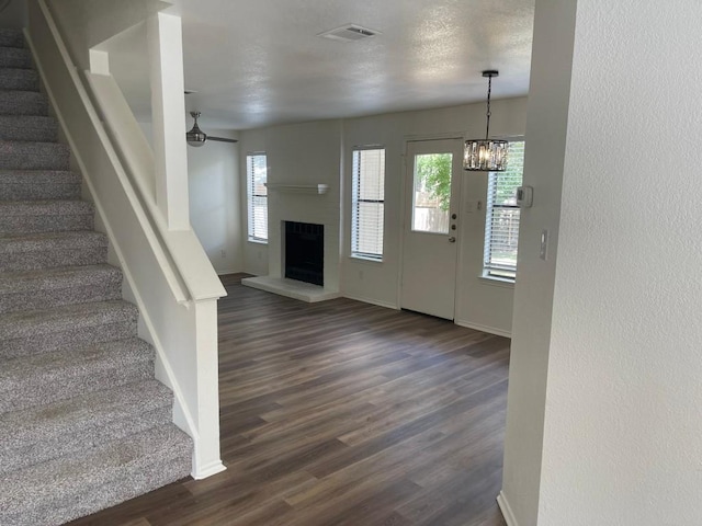 foyer with dark hardwood / wood-style flooring, ceiling fan with notable chandelier, and a textured ceiling