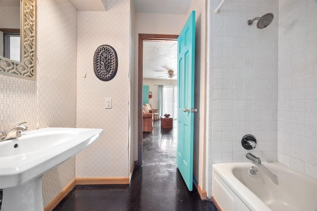 bathroom with ceiling fan, sink, a textured ceiling, and tiled shower / bath