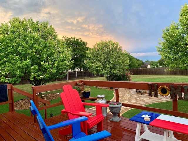 deck at dusk with a fenced backyard and a lawn