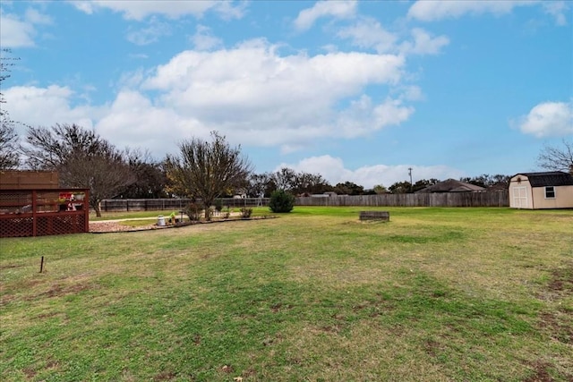 view of yard with a storage shed, an outbuilding, a fenced backyard, and a fire pit