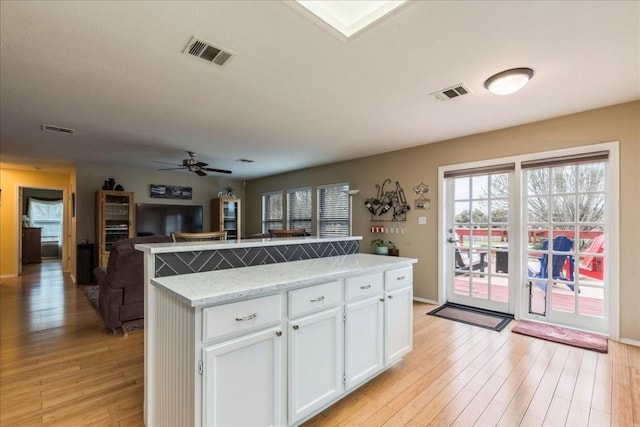 kitchen featuring light wood-style floors, visible vents, and a center island