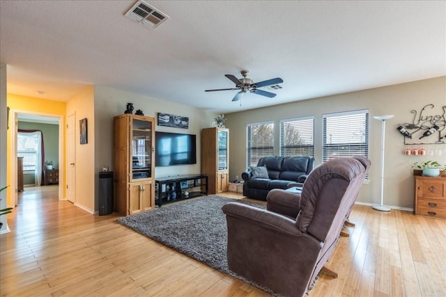 living area with light wood-style floors, baseboards, visible vents, and a ceiling fan