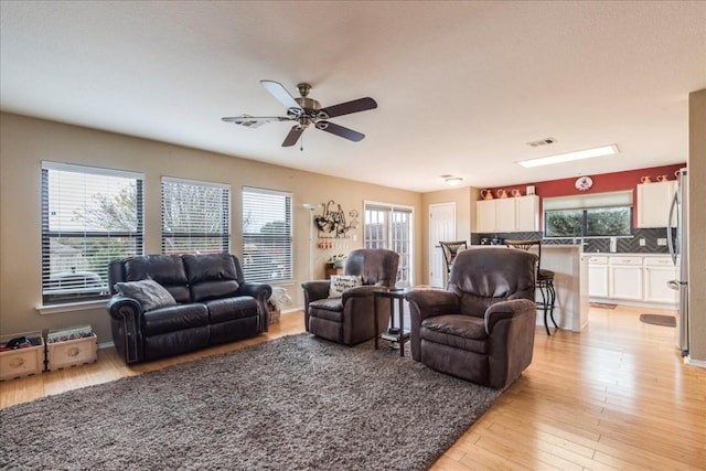 living area featuring light wood-type flooring, visible vents, and a ceiling fan