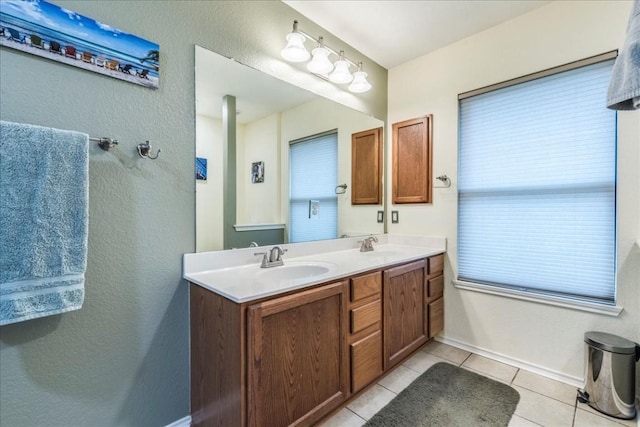 full bathroom featuring double vanity, baseboards, a sink, and tile patterned floors