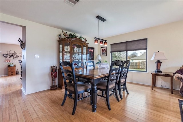 dining room featuring light wood finished floors, visible vents, and baseboards