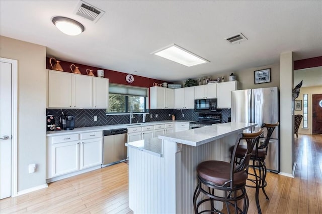 kitchen featuring stainless steel appliances, light countertops, visible vents, and a kitchen breakfast bar