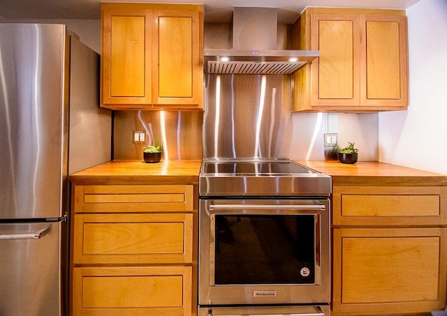 kitchen with wall chimney exhaust hood, wooden counters, and appliances with stainless steel finishes