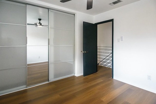 unfurnished bedroom with ceiling fan, a closet, and dark wood-type flooring