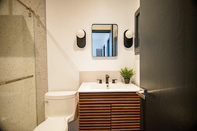 bathroom featuring a shower, decorative backsplash, vanity, and toilet