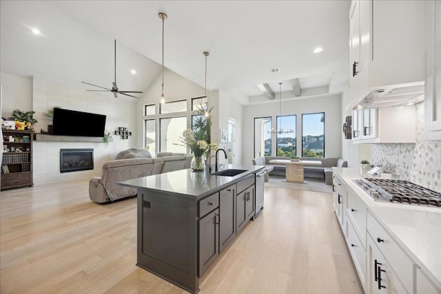 kitchen featuring sink, decorative light fixtures, decorative backsplash, a fireplace, and white cabinets