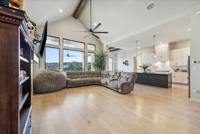 living room with ceiling fan, beam ceiling, light wood-type flooring, and high vaulted ceiling