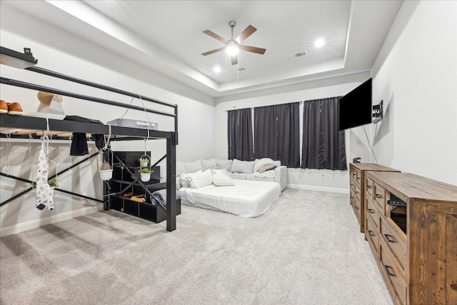 carpeted bedroom featuring a raised ceiling and ceiling fan