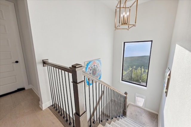 stairway featuring hardwood / wood-style flooring and an inviting chandelier