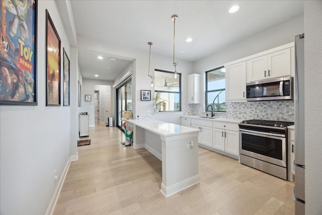 kitchen with white cabinetry, a center island, sink, stainless steel appliances, and pendant lighting