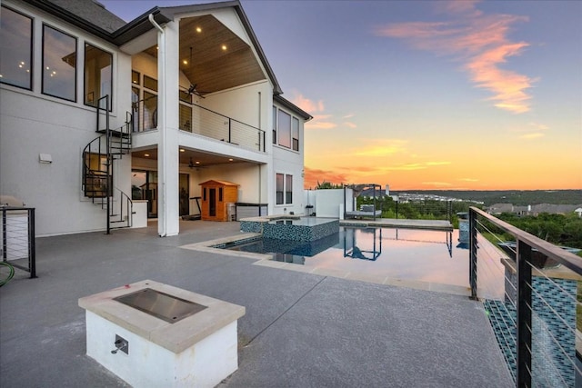 patio terrace at dusk featuring a balcony, area for grilling, an outdoor fire pit, and ceiling fan