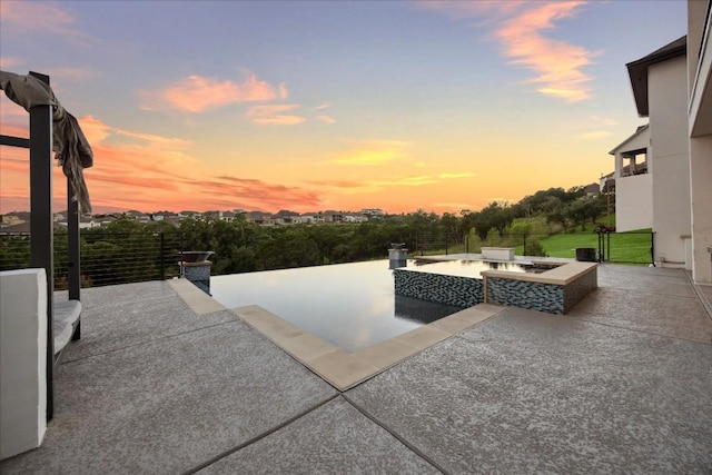 patio terrace at dusk featuring a jacuzzi