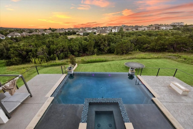 pool at dusk with a lawn and an in ground hot tub