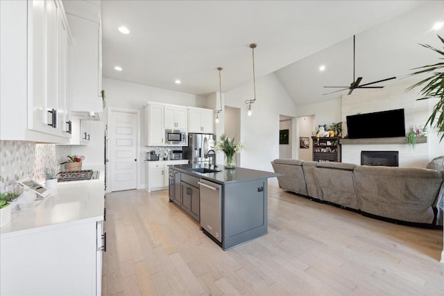 kitchen featuring white cabinets, backsplash, sink, and an island with sink