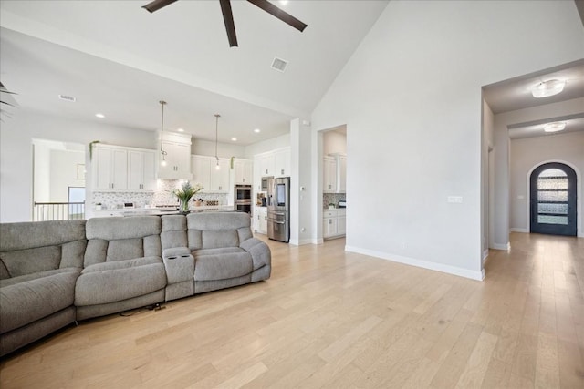 living room featuring light hardwood / wood-style floors, high vaulted ceiling, and ceiling fan